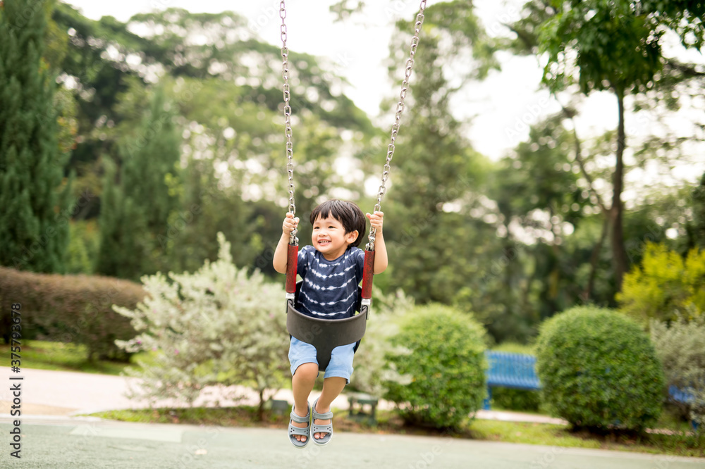 Little bot sitting on a swing in the park Little bot sitting on a swing in the park