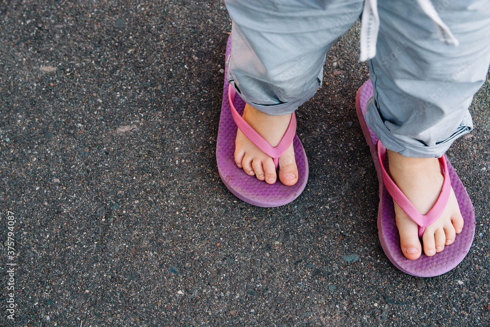Feet of a young toddler in oversize purple flip flops Feet of a young toddler in oversize purple flip flops