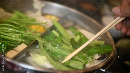 The boiling broth of sukiyaki pot on the dining table