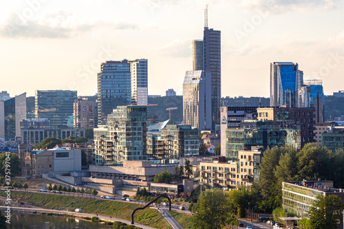 anorama of Vilnius at sunset in August 2020. City buildings. Skyscrapers on the horizon. Blue sky over the city. Clouds and sun at sunset. Summer evening. A quiet day at the weekend © Dmitry Koshelev