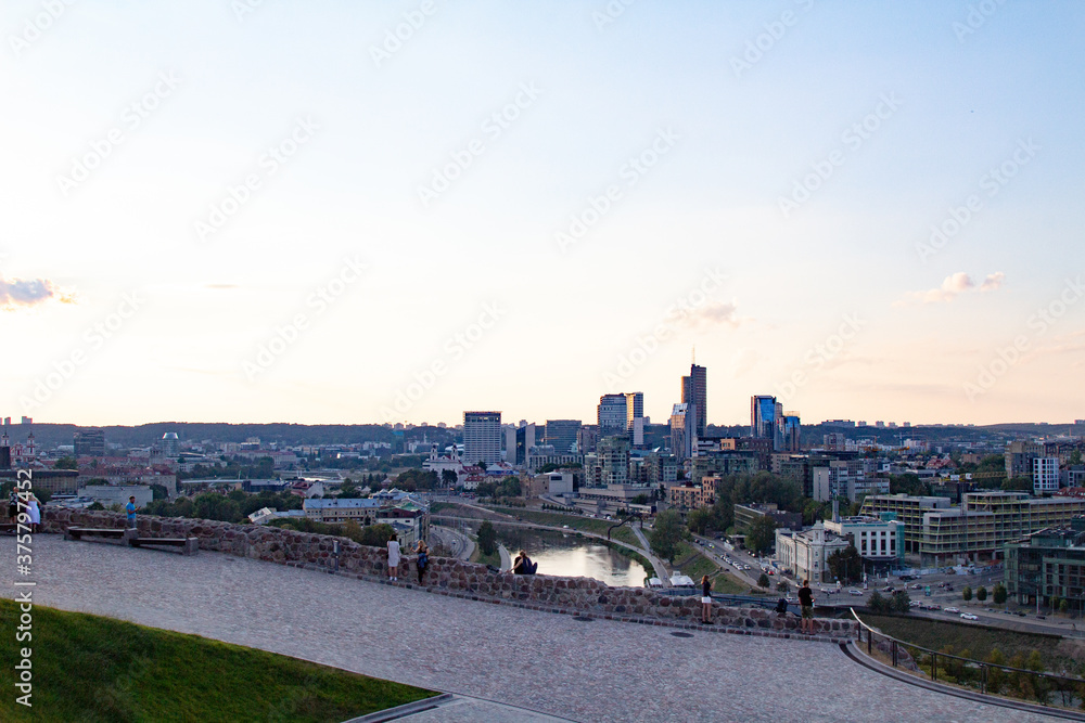 Ruins of a fortress on the mountain. Vilnius. Observation place on the mountain. People are resting and looking down at the city. Young couples spend time together. View of the city from the hill.