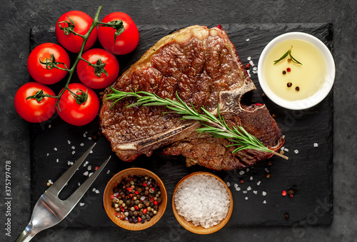 Tableau sur toile grill t-bone steak with ingredients on stone background