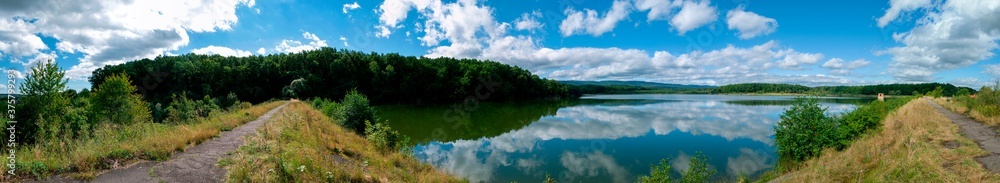 Panoramic view of a calm lake on a sunny summer day Panoramic view of a calm lake on a sunny summer day