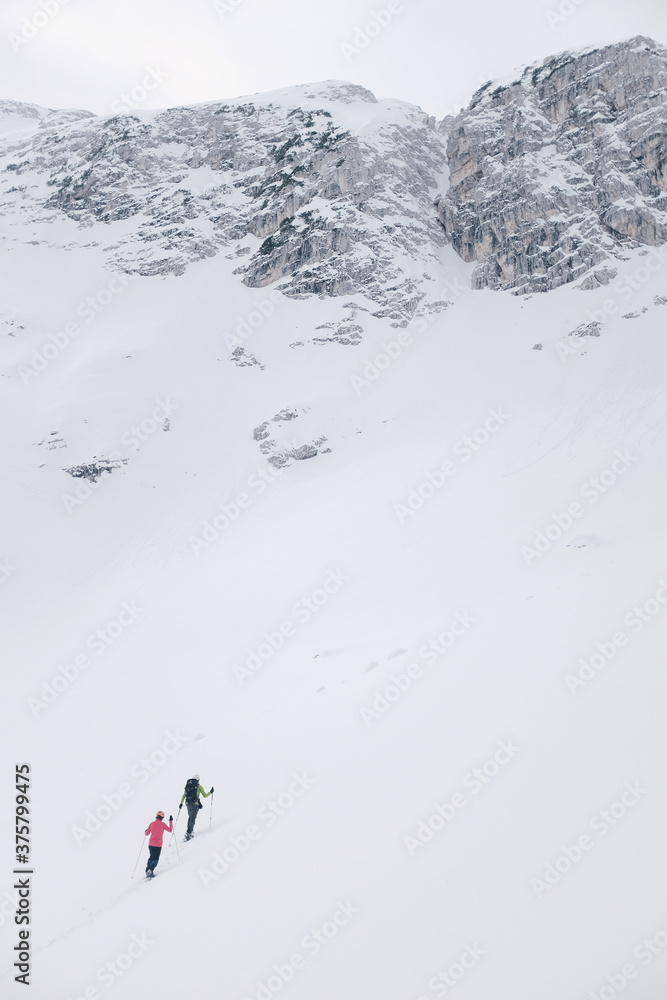 Hikers ascending through snow to big rocks Hikers ascending through snow to big rocks