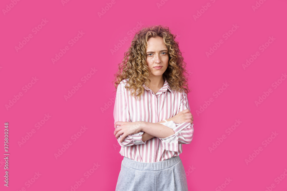 A side shot of a beautiful upset woman with curly hair holding her arms folded. A side shot of a beautiful upset woman with curly hair holding her arms folded.