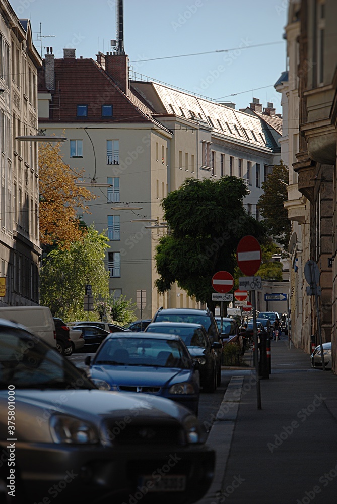Obraz premium Ein Stadtbild mit enger Gasse, Häusern, Stromleitungen und einer Handyantenne am Dach.