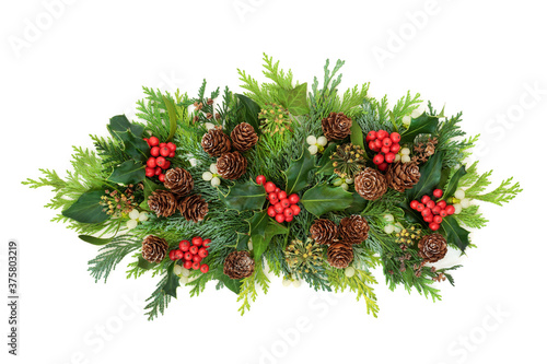 Beautiful winter Christmas & New Year flora arrangement with holly, cedar cypress fir leaves, mistletoe, pine cones & ivy on white background. Festive decoration for the holiday season. Top view.