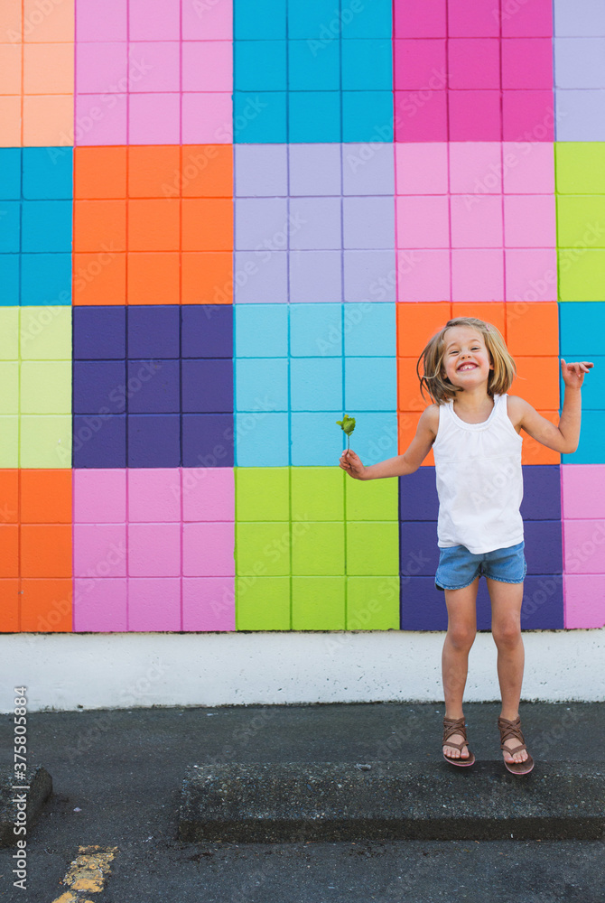 Cute young girl having fun jumping near colorful wall in summer Cute young girl having fun jumping near colorful wall in summer