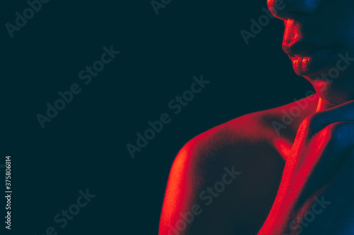 Male silhouette. Neon light. Unrecognizable black man with strong shoulder hand on chin isolated on dark copy space. Masculine power. Ethnic problems. Human confidence photo