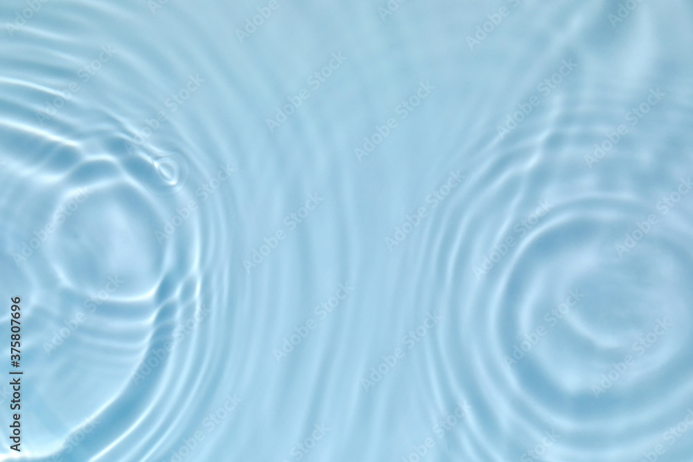 Blurred transparent blue colored clear calm water surface texture with splashes and bubbles. Trendy abstract nature background. Water waves in sunlight with copy space.