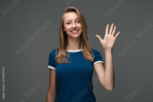 Wallpaper Mural Cheerful girl with blonde straight hair waving raised palm. Say HELLO. Human emotions, facial expression concept. Torontodigital.ca