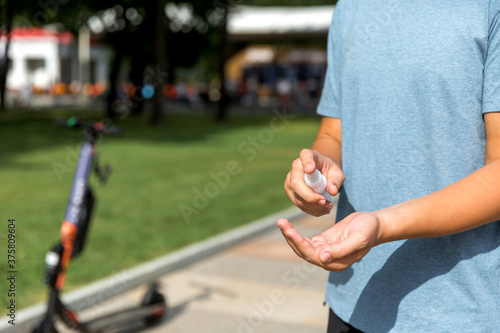 A teenager treats his hands with a sanitizer in the Park.