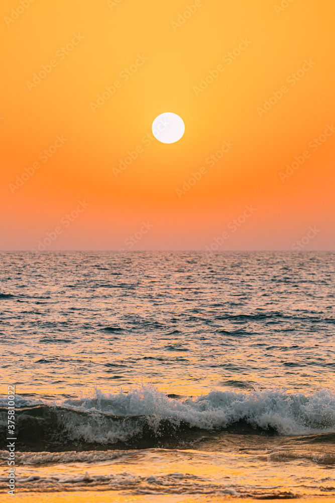 Sunset Sun Shine Above Sea. Natural Sunrise Sky Warm Colors Over Ripple Sea. Ocean Water Foam Splashes Washing Sandy Beach