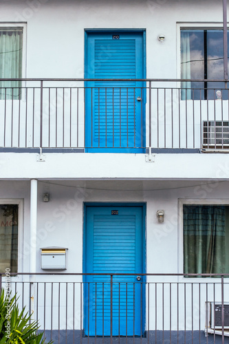 Two floors of apartments with symmetric blue front doors photo