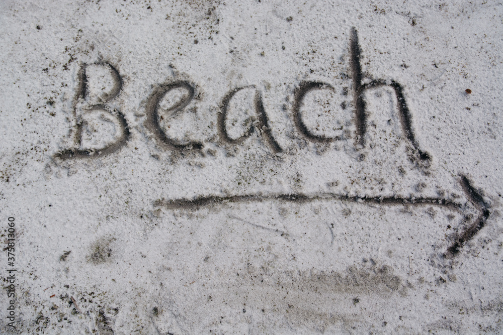 Handwritten sign in sand pointing to a beach Handwritten sign in sand pointing to a beach