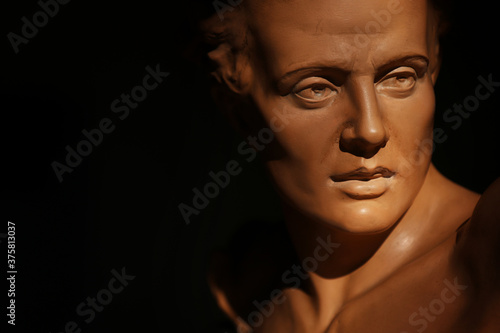 Ritratto di giovane uomo, primo piano di testa in terracotta di provenienza europea, scultura su fondo scuro con spazio per testo 