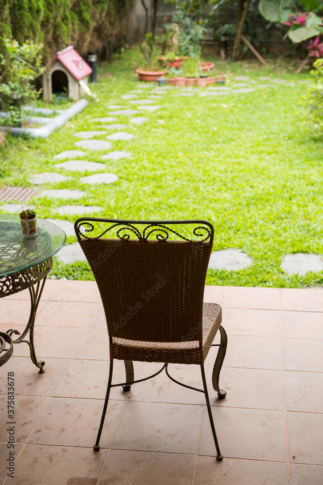 Iron rattan chair at porch facing yard with meadow Iron rattan chair at porch facing yard with meadow