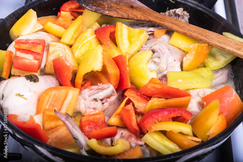Cooking chicken with peppers, tomatoes and herbs according to a classic Italian recipe in a pan - Roman chicken, close-up, top view
