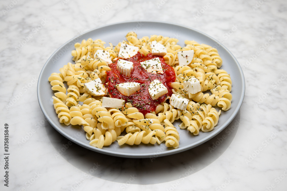 Pasta with tomato sauce and cheese on a marble table Pasta with tomato sauce and cheese on a marble table