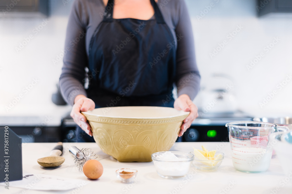 woman standing at kitchen benchtop with mixing bowl and ingredients for baking woman standing at kitchen benchtop with mixing bowl and ingredients for baking