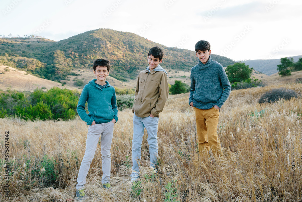 Three friends standing in an open field of grass Three friends standing in an open field of grass