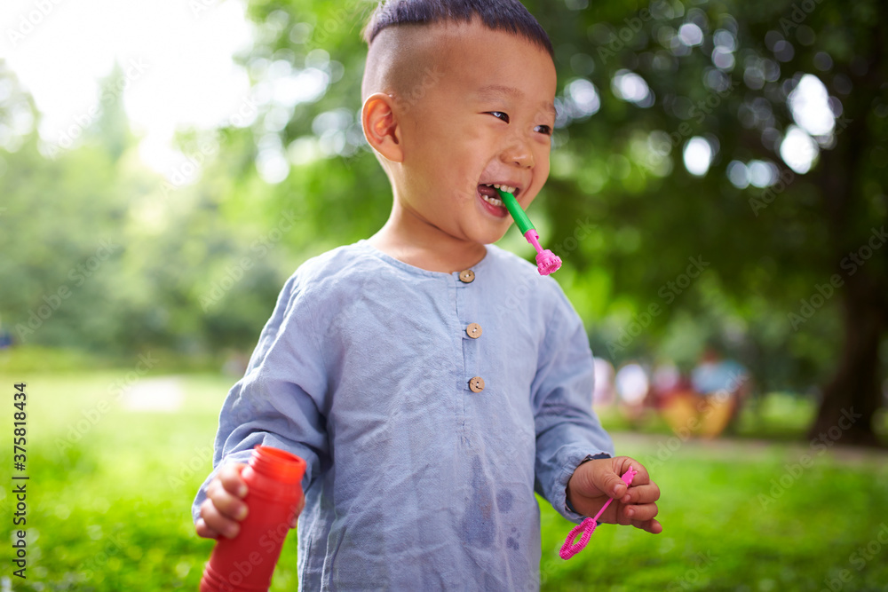 little asian boy playing bubble in the park little asian boy playing bubble in the park
