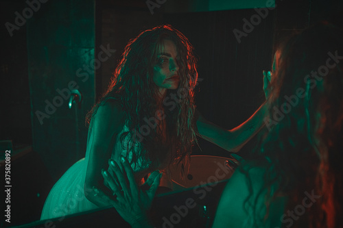 Obraz na płótnie mysterious woman wearing wedding dress looking at her scary reflection in a mirror. w salonie