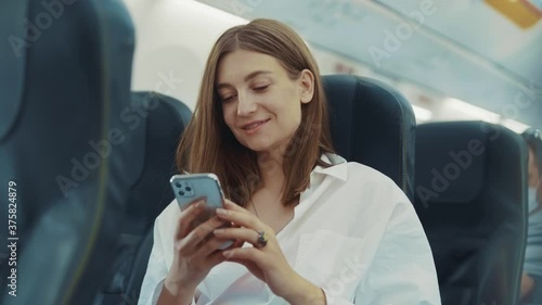 Smiling happy young woman use phone on plane lady vacation travel transportation pretty journey tourism trip transport traveler