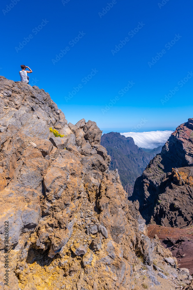 A young woman sits resting and looking at the views of the Roque de los Muchachos national park on top of the Caldera de Taburiente, La Palma, Canary Islands. Spain