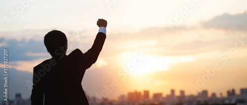 silhouette hand raised fist business man with sun lighting in morning.