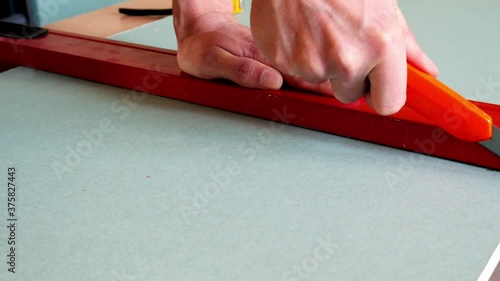 Man cutting a green plasterboard with a knife