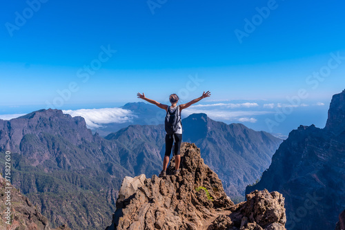 A young woman on top of the volcano of Caldera de Taburiente near Roque de los Muchachos one summer afternoon with open arms, La Palma, Canary Islands. Spain