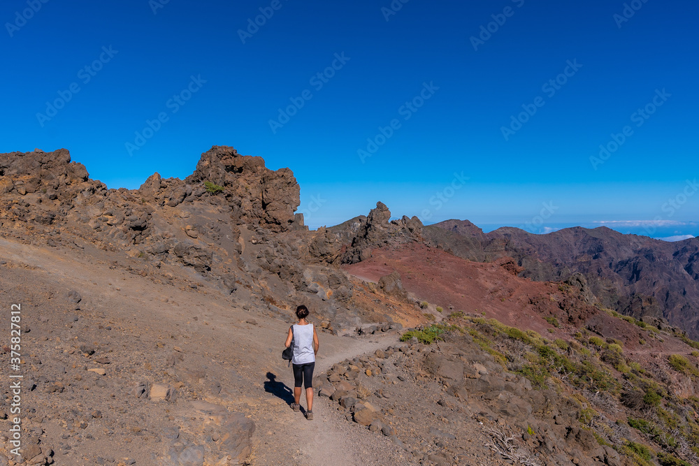 A young woman walking atop the Caldera de Taburiente volcano near Roque de los Muchachos one summer afternoon, La Palma, Canary Islands. Spain