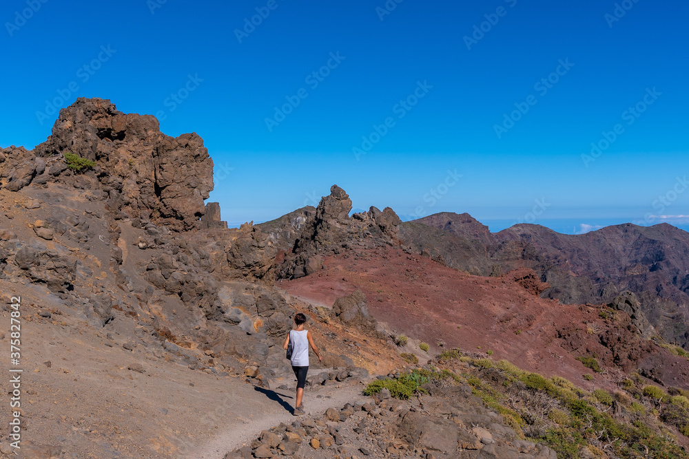 A young woman walking atop the Caldera de Taburiente volcano near Roque de los Muchachos one summer afternoon, La Palma, Canary Islands. Spain A young woman walking atop the Caldera de Taburiente volcano near Roque de los Muchachos one summer afternoon, La Palma, Canary Islands. Spain