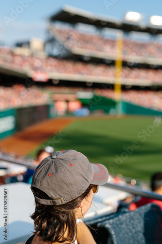 Woman in baseball cap watching professional game