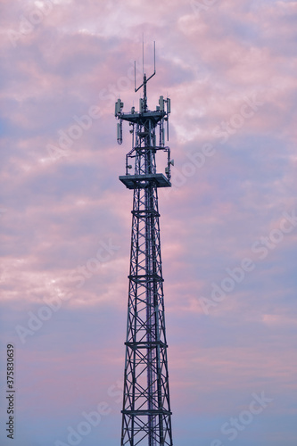 Cell phone tower against a pastel colored sky during sunset.