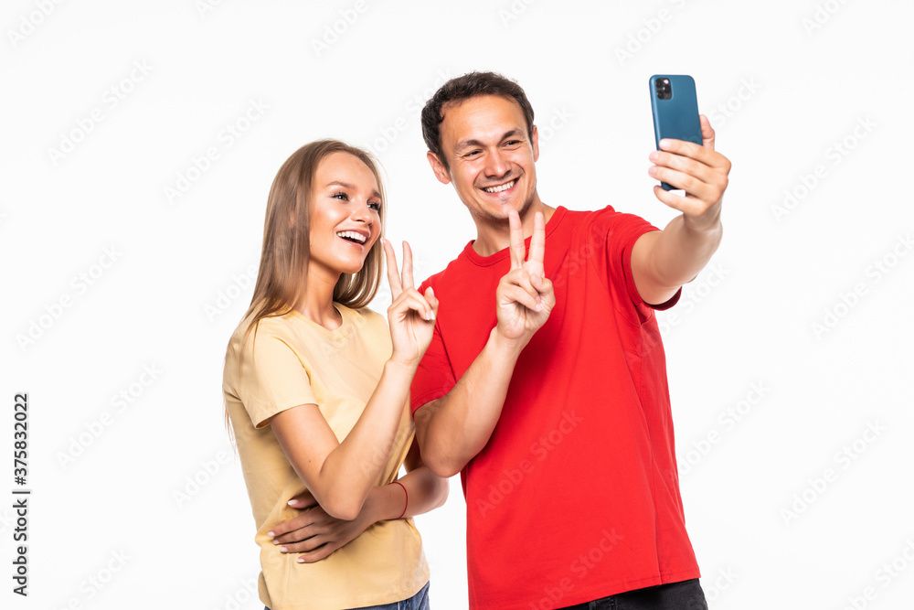 Young couple making a selfie or video call together with a mobile phone isolated in white background