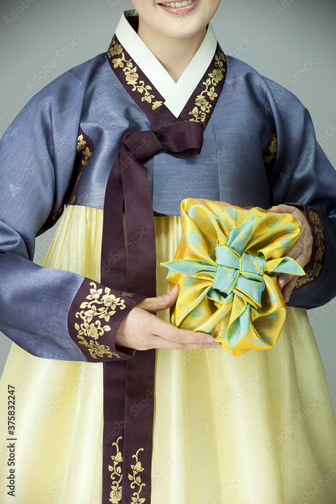 young woman in korean traditional clothing holding gift box