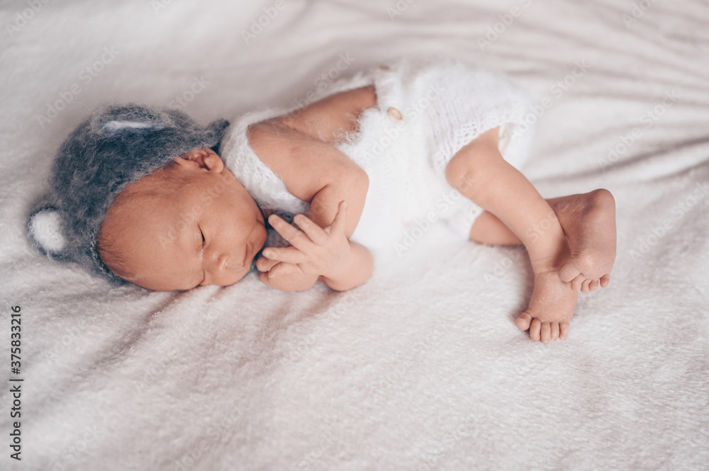 Cute emotional newborn little baby boy sleeping in crib in a knitted suit with ears. Baby goods packaging template. Healthy child, concept of hospital and happy motherhood. Infant baby. Nursery Cute emotional newborn little baby boy sleeping in crib in a knitted suit with ears. Baby goods packaging template. Healthy child, concept of hospital and happy motherhood. Infant baby. Nursery