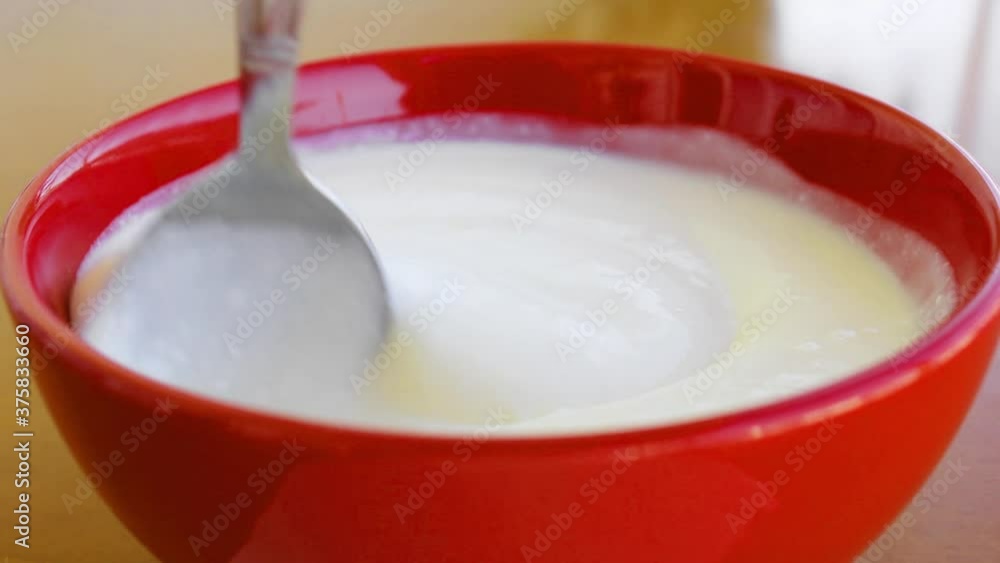Fresh creamy yogurt in a bowl, stirred with a spoon, slow motion, food concept Fresh creamy yogurt in a bowl, stirred with a spoon, slow motion, food concept