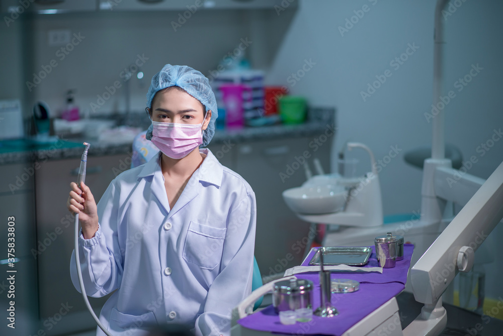 female dentist holds a drill in his office. female dentist holds a drill in his office.