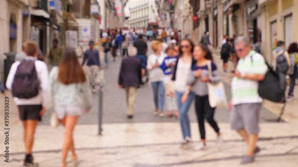 People stroll at bottom end of pedestrian street in Lisbon downtown, blurred view. Tourism at European city in summer time, old historical part of town crowded with visitors People stroll at bottom end of pedestrian street in Lisbon downtown, blurred view. Tourism at European city in summer time, old historical part of town crowded with visitors