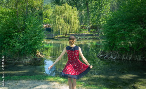 girl in red dress dances and has fun in the middle of the Italian nature