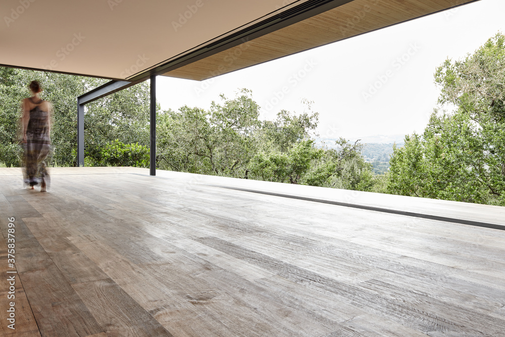 Woman walking on indoor/outdoor deck at modern design home Woman walking on indoor/outdoor deck at modern design home