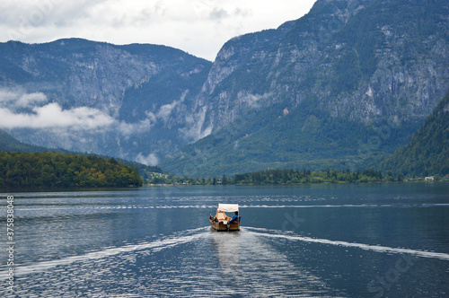 Wooden boat with driver on Hallstatter lake with mountains in the background, Austria