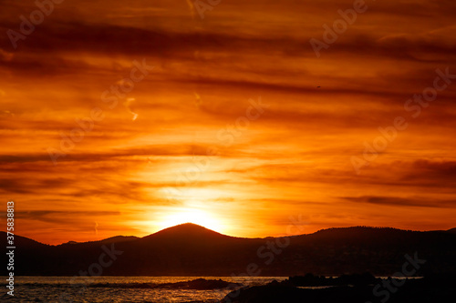 silhouette of hills on the seashore at sunset or sunrise with cloudy sky