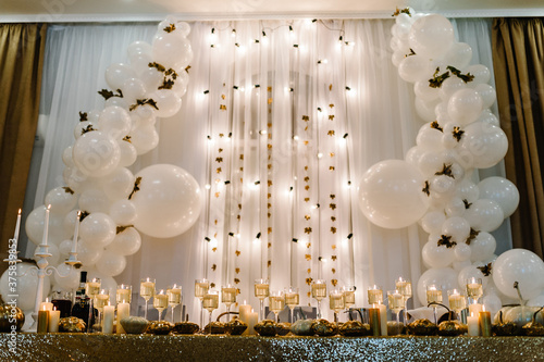 Table setting for wedding. Decorated arch for wedding ceremony. White balloons, candles, autumn leaves and small pumpkins. Autumn location and Halloween decor.