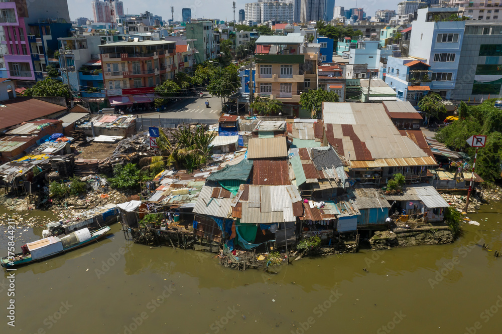 Old shacks made from Corrugated iron in contrast with modern buildings along the waterfront of Kenh Te Canal in Ho Chi Minh City, Vietnam