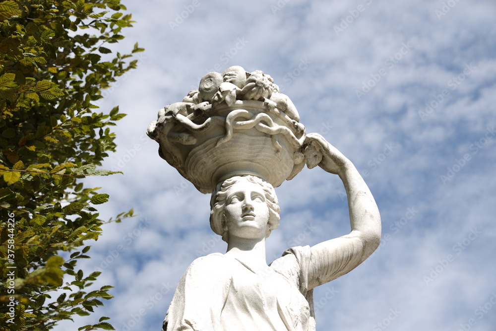 Antike Statue von einer Frau mit einer Obstschale auf dem Kopf