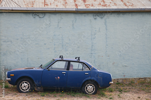 an old blue car left on the side of the road photo